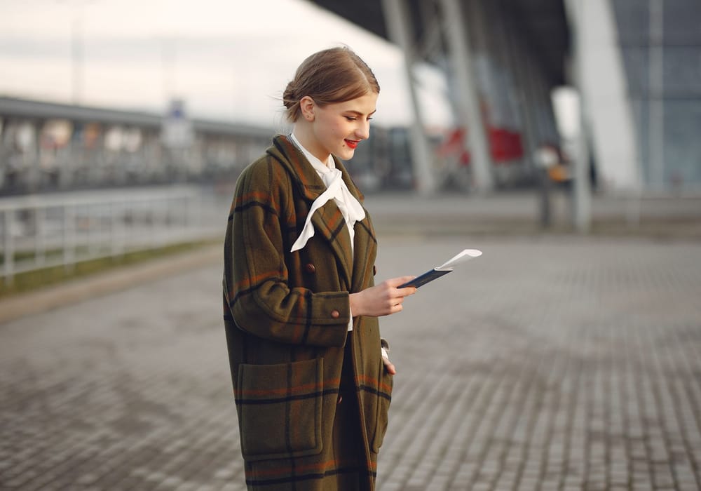 A traveller checking her passport outside an airport terminal